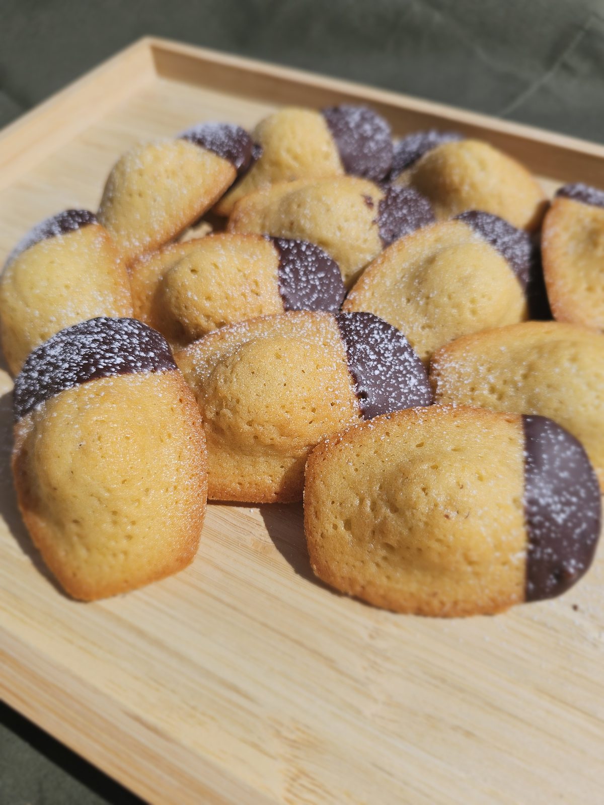 Fresh madeleines dipped in chocolate and dusted with icing sugar