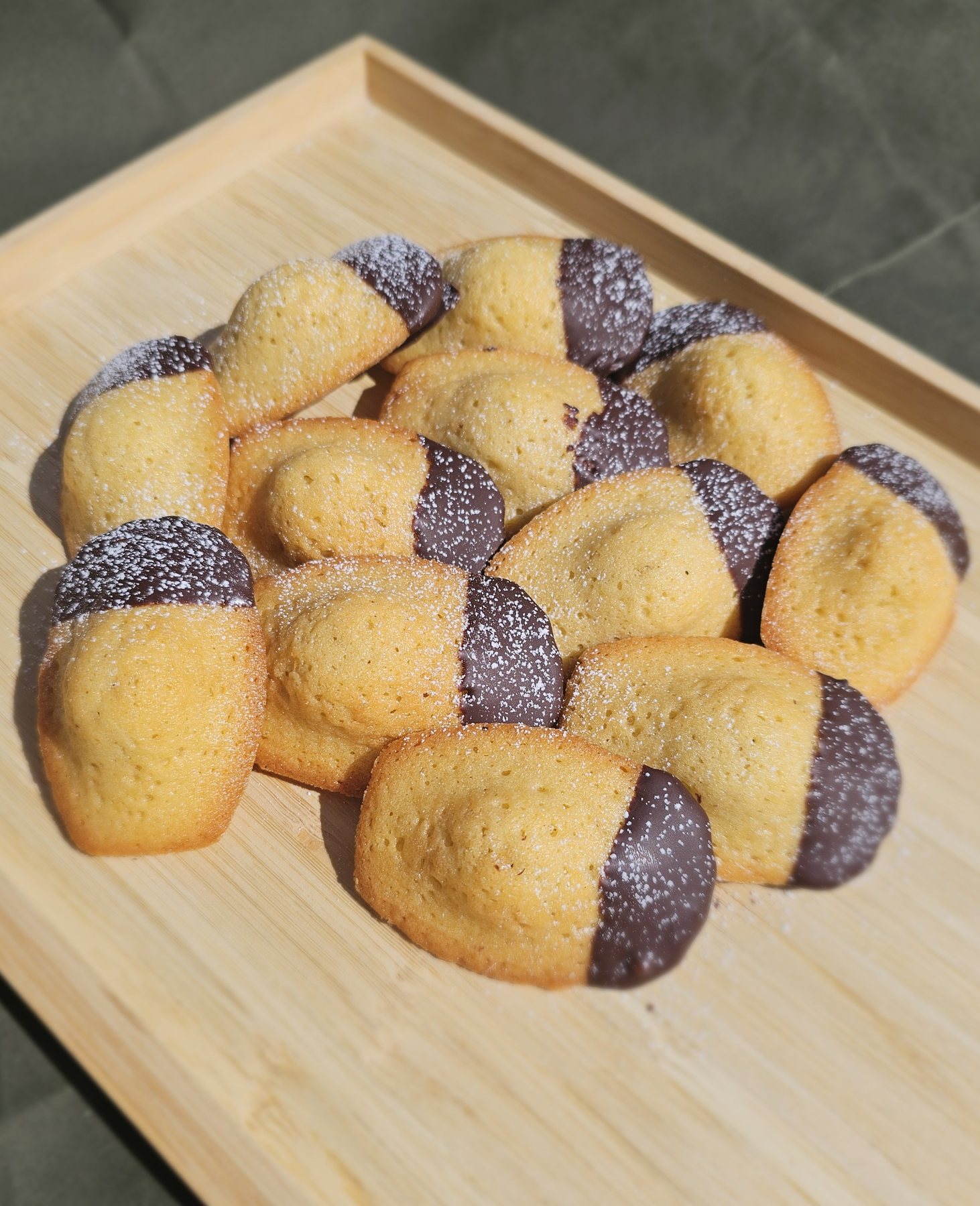 Chocolate dipped madeleines dusted with icing sugar